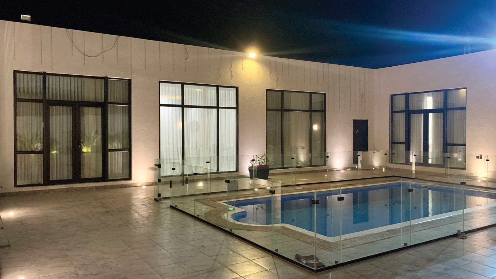 فيلا بمسبح وواجهة كاملة من نوافذ وأبواب UPVC مضاءة ليلاً