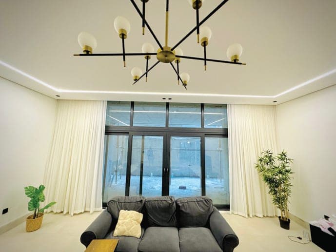 صالة معيشة بنوافذ UPVC بيضاء على امتداد الجدار وثريا