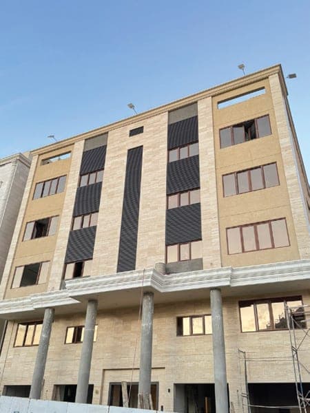 عمارة سكنية من خمسة أدوار بواجهة حجرية ونوافذ داكنة